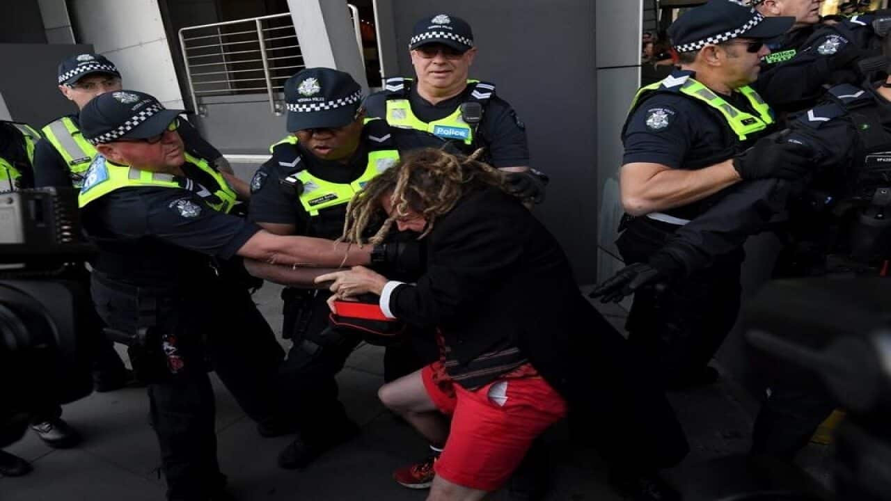 Police try to grab a protester outside a Melbourne centre.