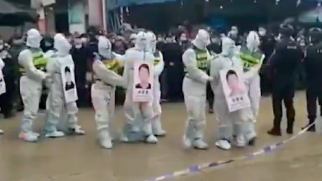 Four suspects in hazmat suits were reportedly paraded Tuesday in front of a large crowd in Guangxi region.