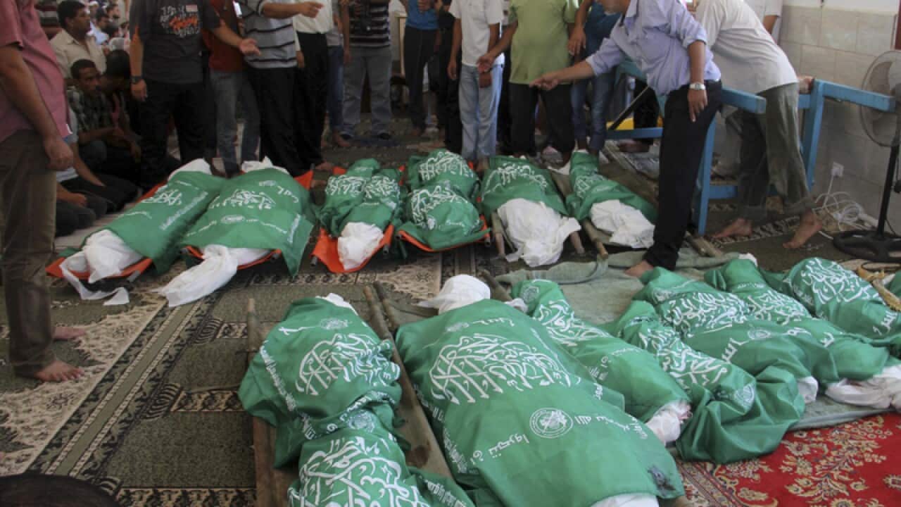 Palestinians gather around the Hamas green flag-draped bodies