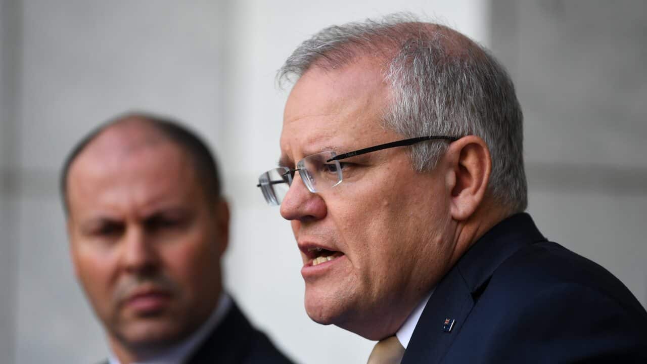 Treasurer Josh Frydenberg listens as Prime Minister Scott Morrison addresses economic stimulus measures.
