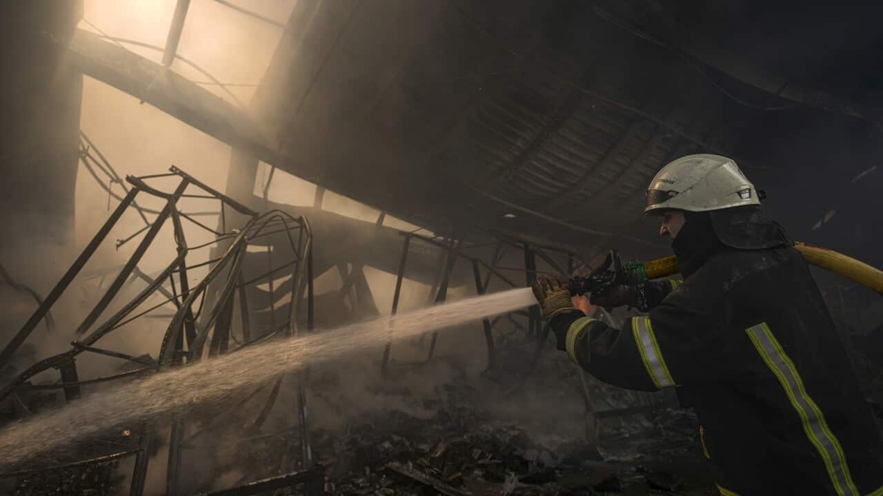 A Ukrainian firefighter hoses down a destroyed warehouse after a Russian bombardment.