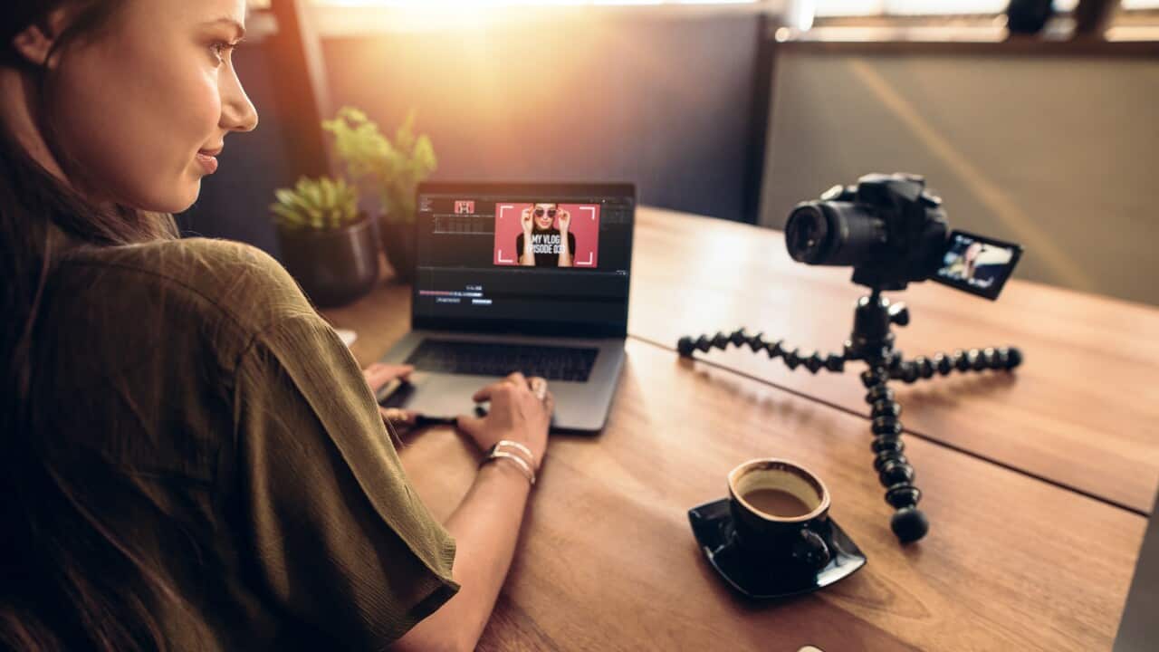 Young female vlogger looking at her camera while editing her vlo
