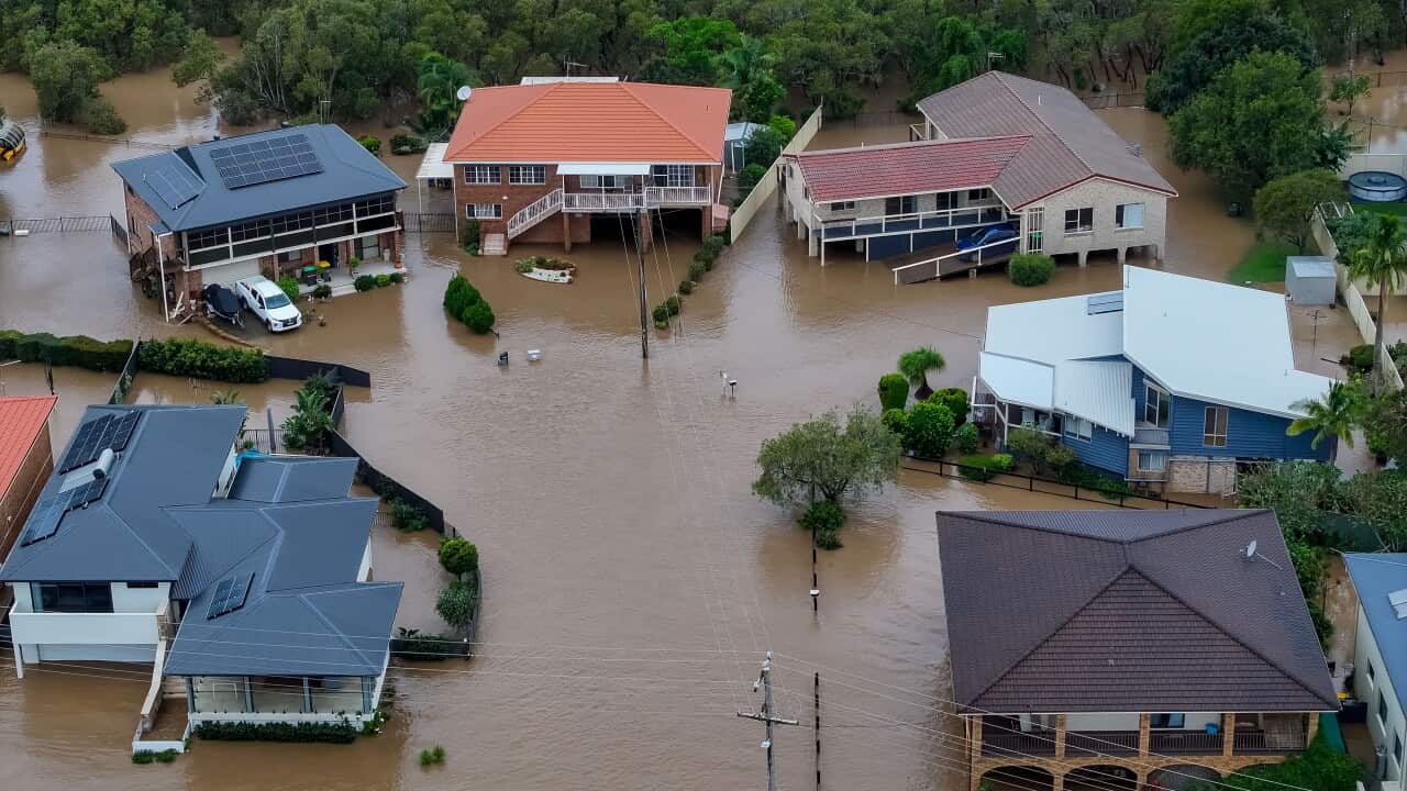 An aerial shot of houses submerged in brown floodwater.