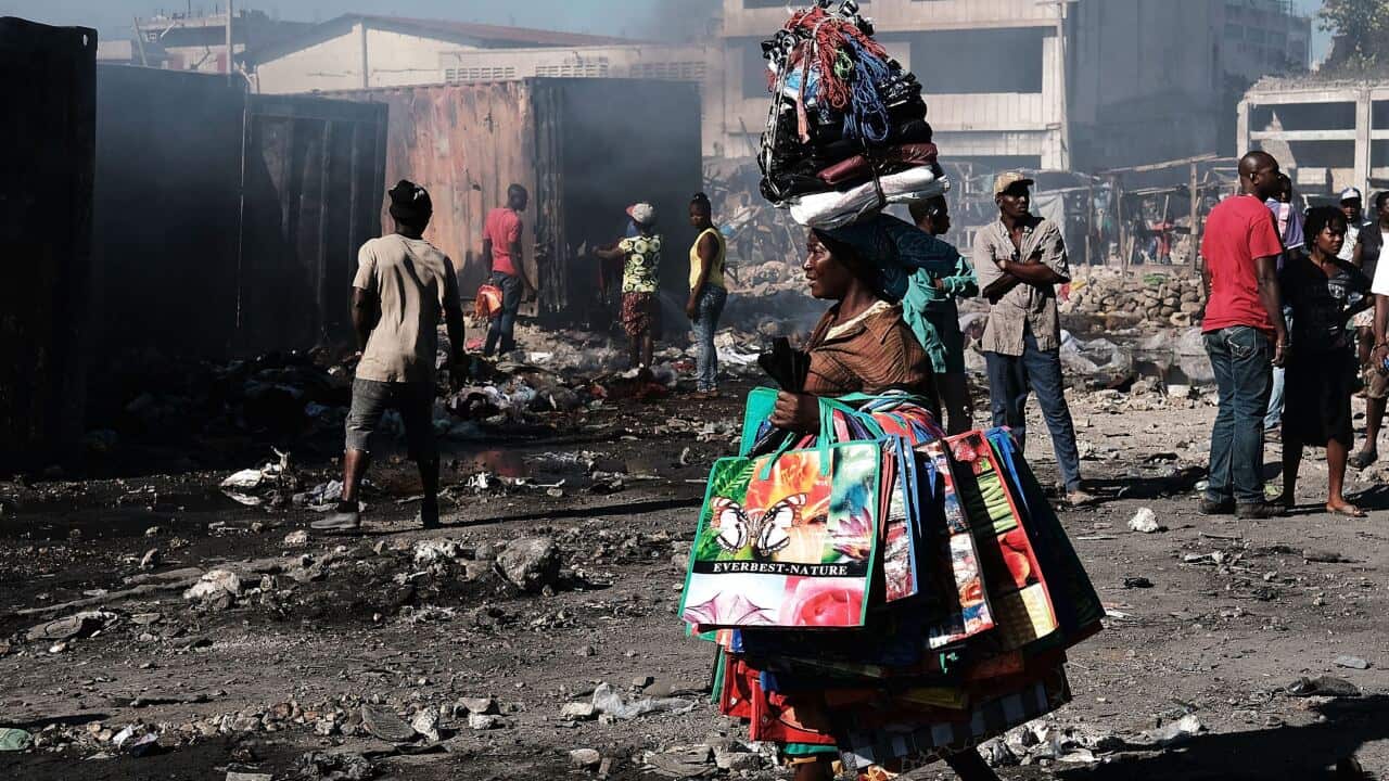 Haitians gather outside of Port-au-Prince's destroyed historic Iron Market after a fire on February 14, 2018 in Port-au-Prince, Haiti.