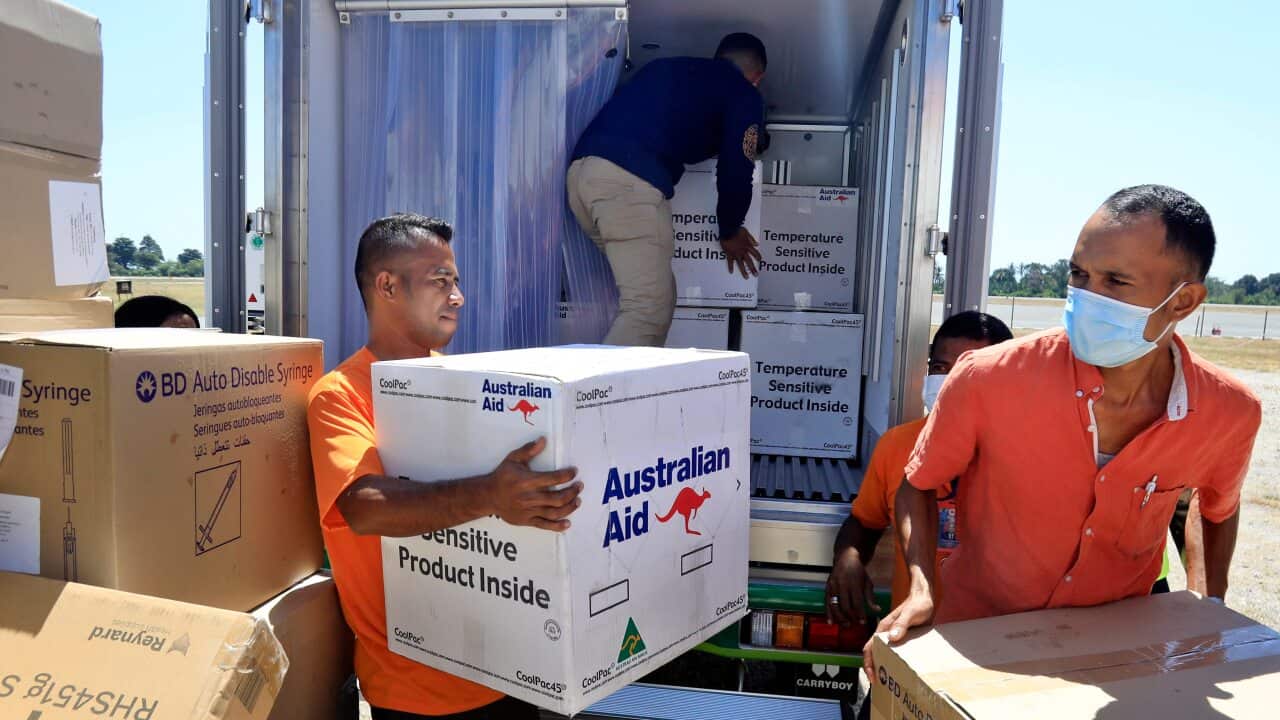 Workers load COVID-19 vaccines donated by the Australian government into a truck after their arrival in Dili in July 2021.