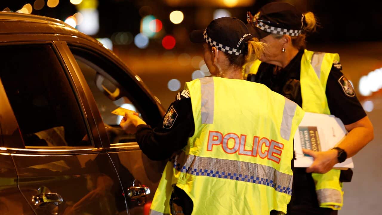 Police speak to a driver at a road block near the Queensland-NSW border.