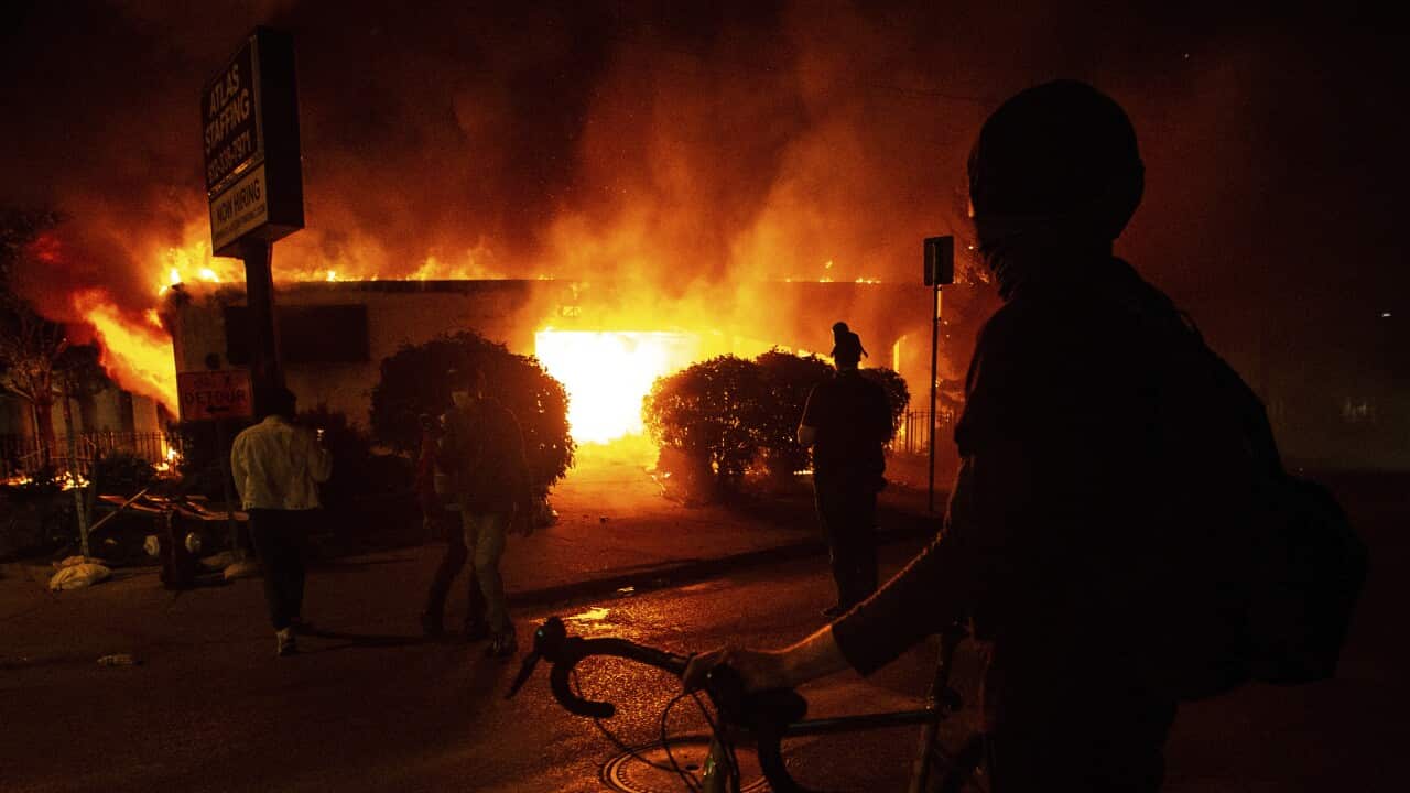 A protester looks on at a burning building in Minneapolis, early Saturday, May 30, 2020, amid protests against the death of George Floyd in police custody on Memorial Day. (Khadejeh Nikouyeh/News & Record via AP)