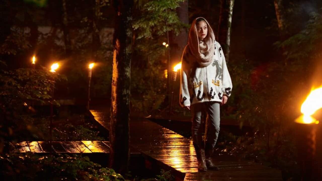 Woman walking along rainy pathway at night.