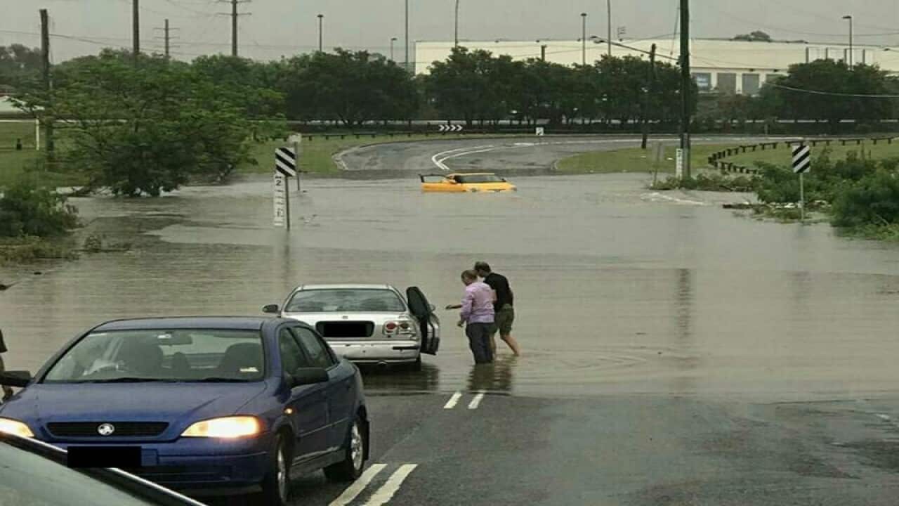 Vehicles drive through a flooded road in Rocklea, Brisbane.