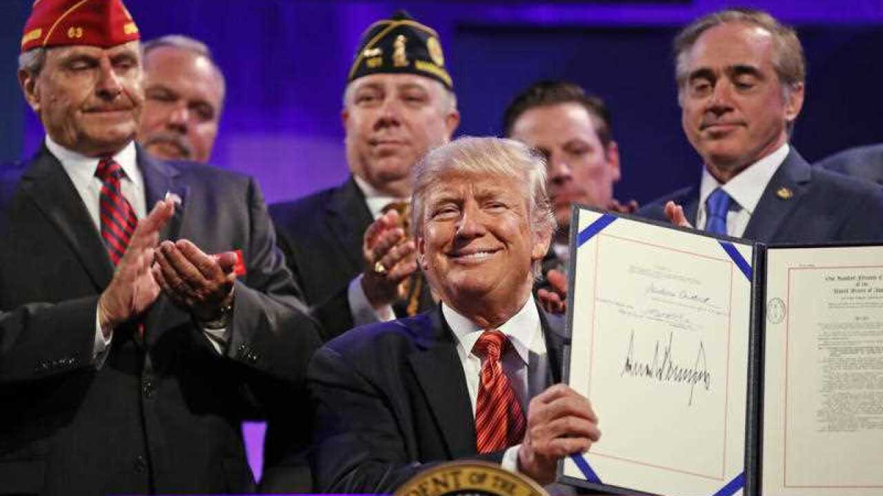 President Donald Trump holds up a signed Veterans Appeals Improvement and Modernization Act, Wednesday, Aug. 23, 2017