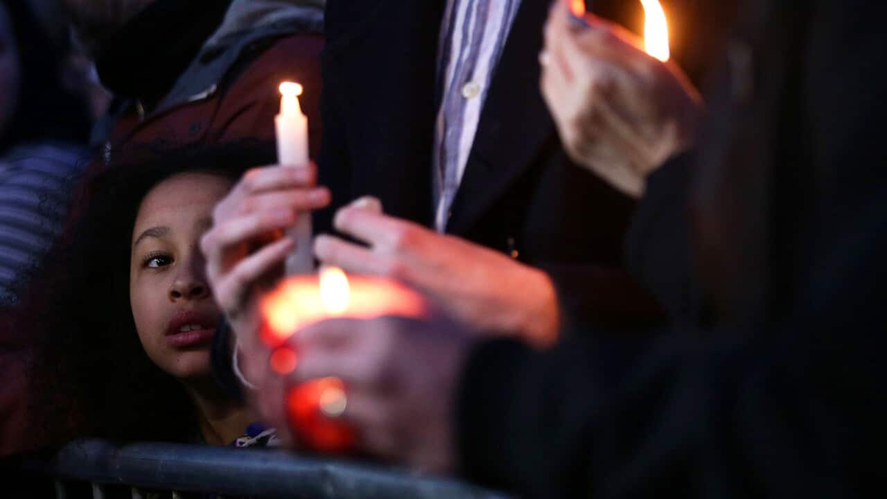 A young girl looks on as members of the public hold candles during a candlelight vigil in Trafalgar Square, London, in honor of recent terror attack victims.