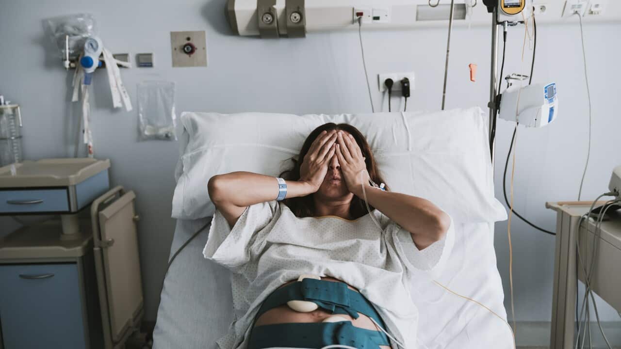 Stressed pregnant woman lying on bed in hospital