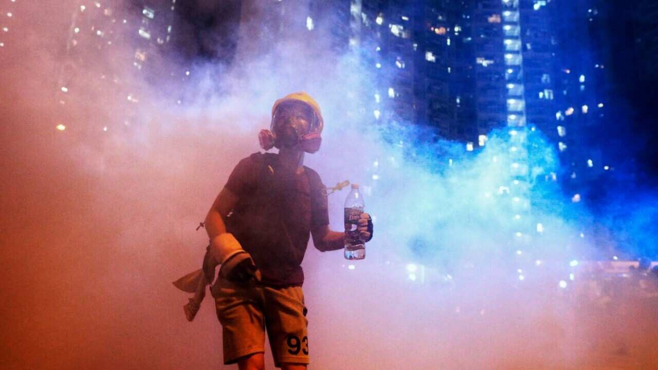A protester stands in the midst of tear gas during confrontation with police in Hong Kong during the early hours of Sunday, Aug. 4, 2019.