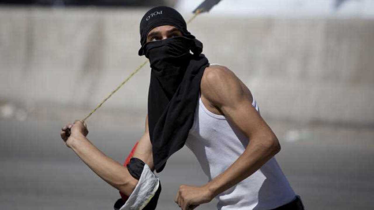 A Palestinian uses a sling shot with stones during clashes with Israeli troops.