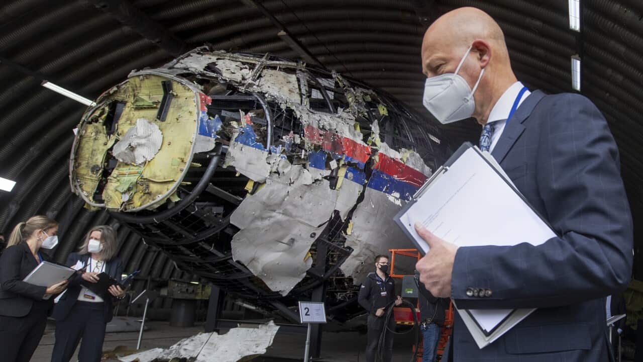 People standing near the reconstructed wreckage of Malaysia Airline flight MH17.