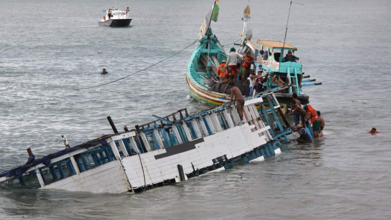 Rescuers check the wreckage of a people smuggler's boat seen half submerged after being towed near the coast of Puger village in East Java province in 2011.