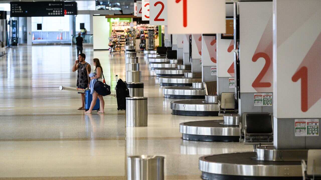 Passengers in an usually quiet baggage arrivals area at Sydney Domestic Airport, Friday, March 20, 2020.