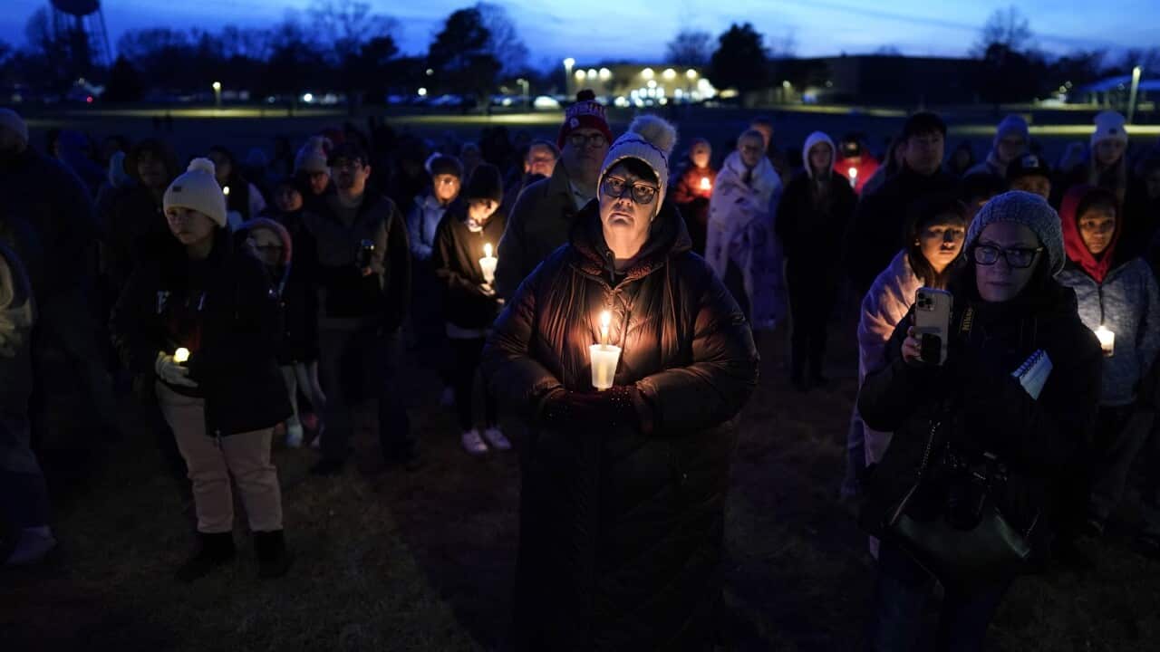 Local residents pray during a candlelight vigil following the shooting at Perry High School (AAP)