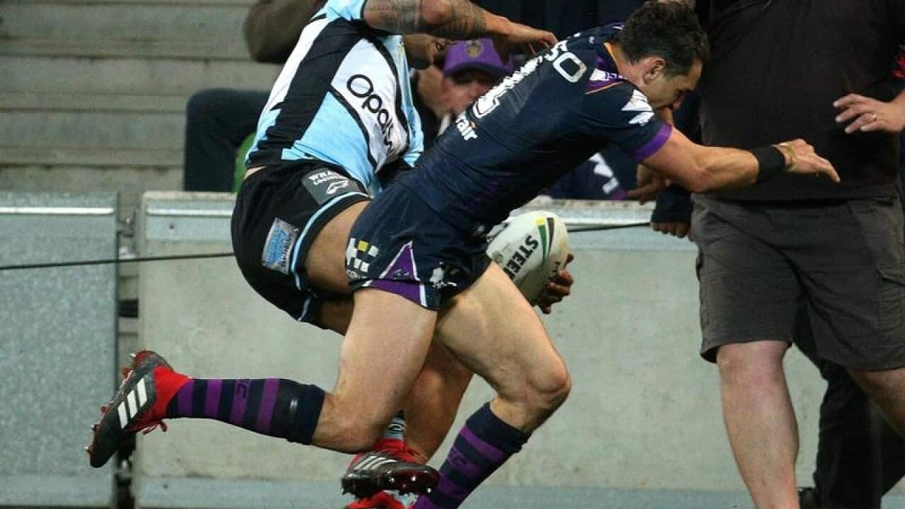 Billy Slater of the Storm (R) tackles Sosaia Feki of the Sharks