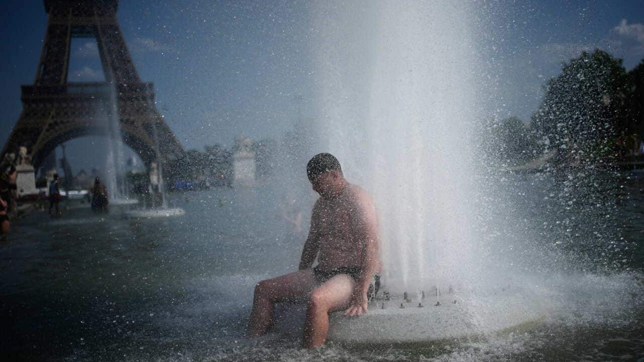 A person cools off at Trocadero fountain near the Eiffel Tower during a heat wave in Paris, Wednesday, June 24, 2026.