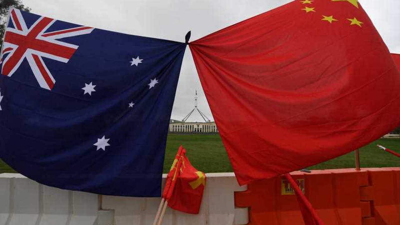Parliament House is seen behind an Australian and a Chinese flag outside Parliament House in Canberra, Thursday, March 23, 2017