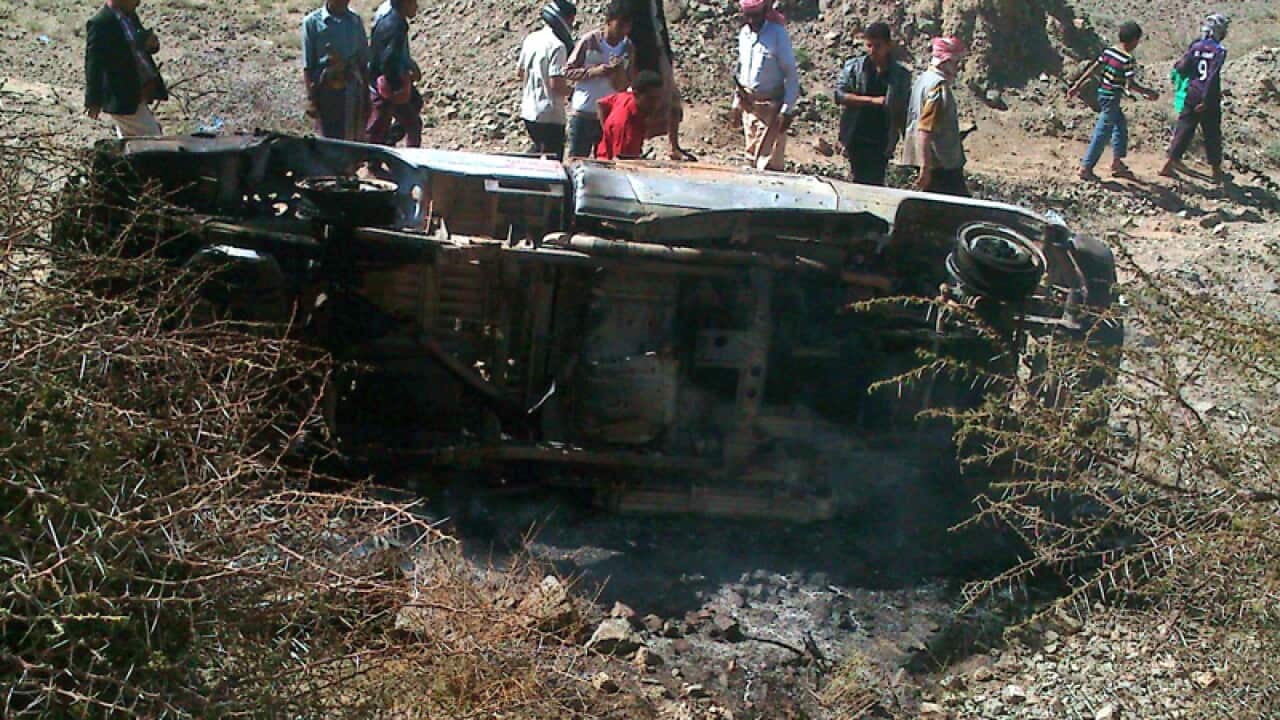Yemenis stand around a pickup truck after an alleged drone attack