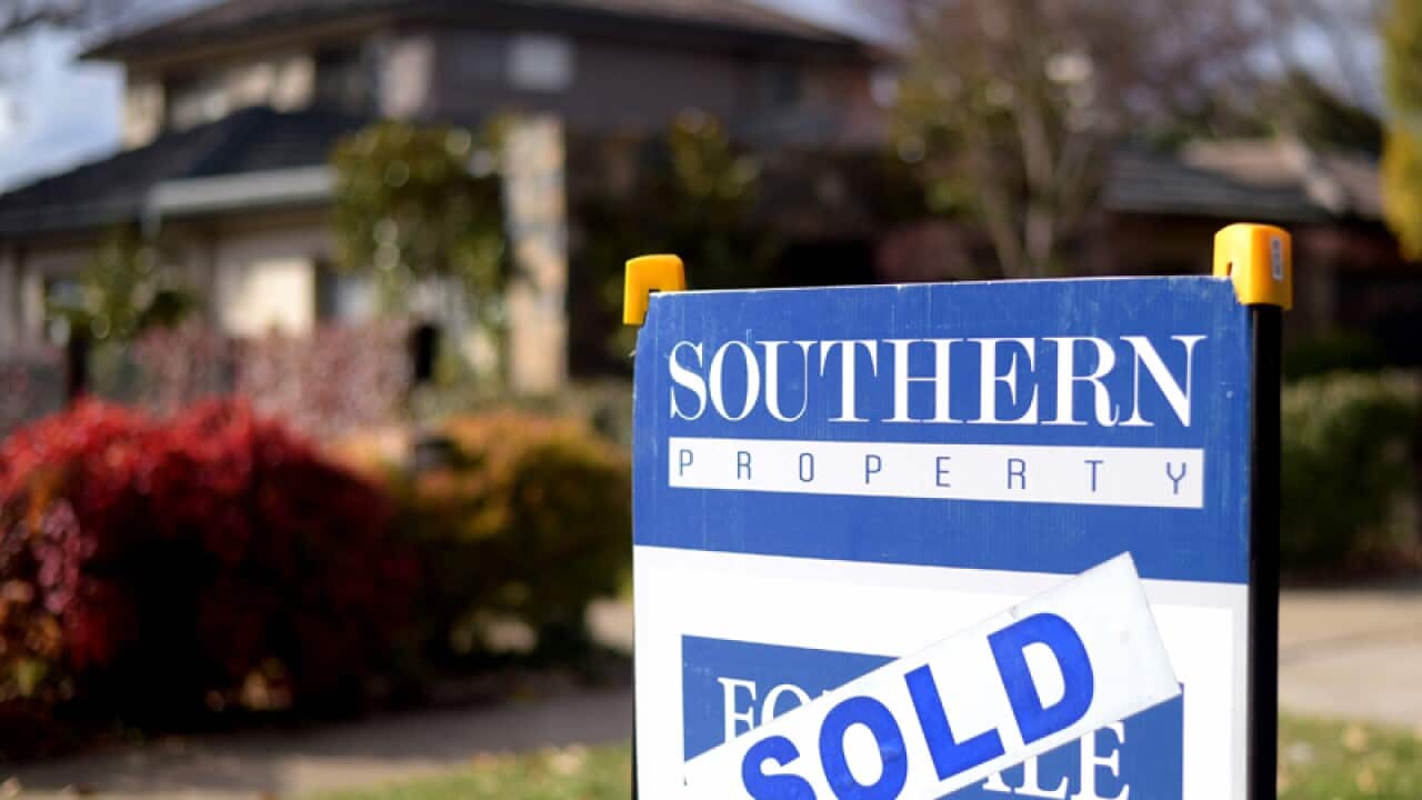 A sale sign is seen in front of a house