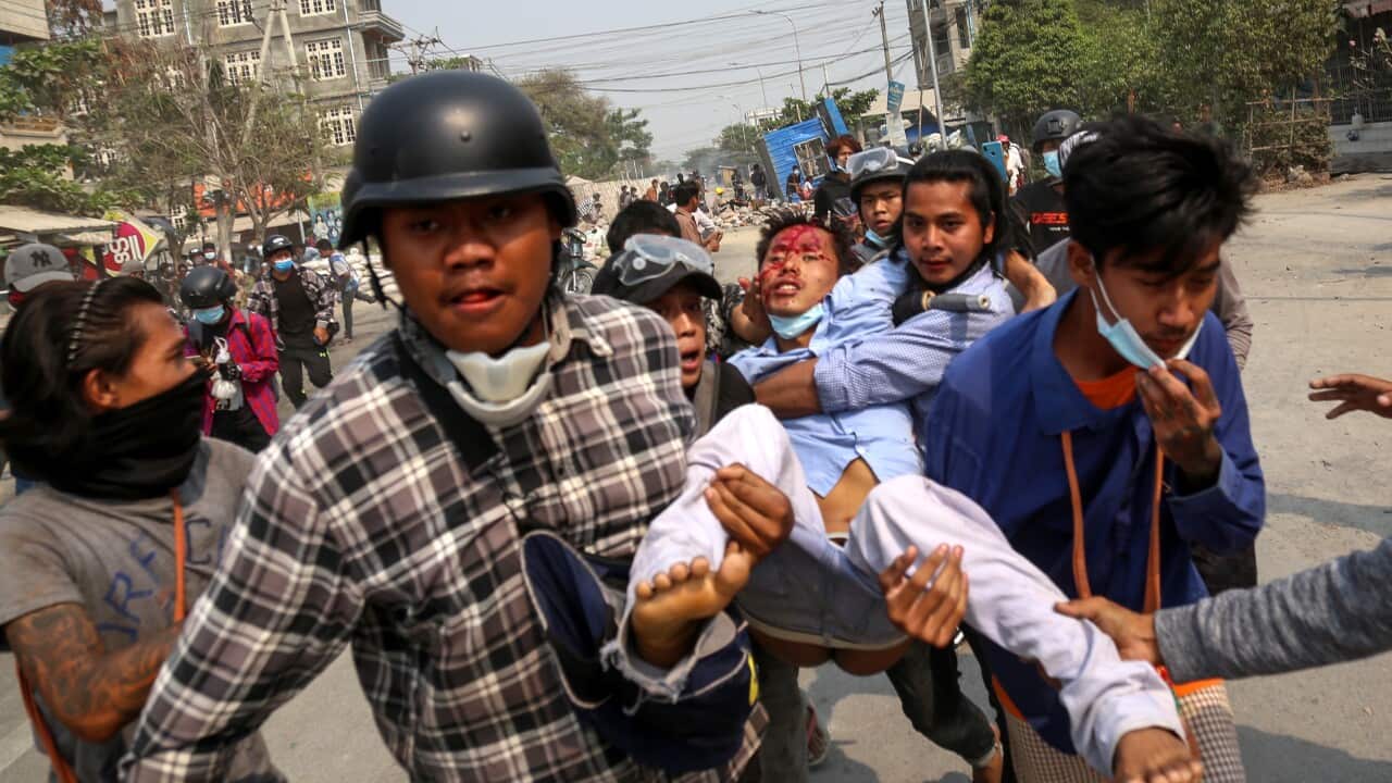 An injured anti-coup demonstrator is carried during a protest in Mandalay, Myanmar, 22 March 2021.