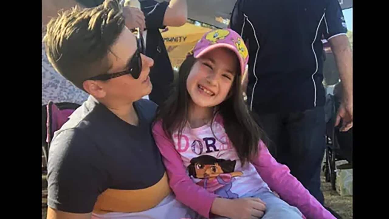 A girl sitting on a woman's lap in the sunshine