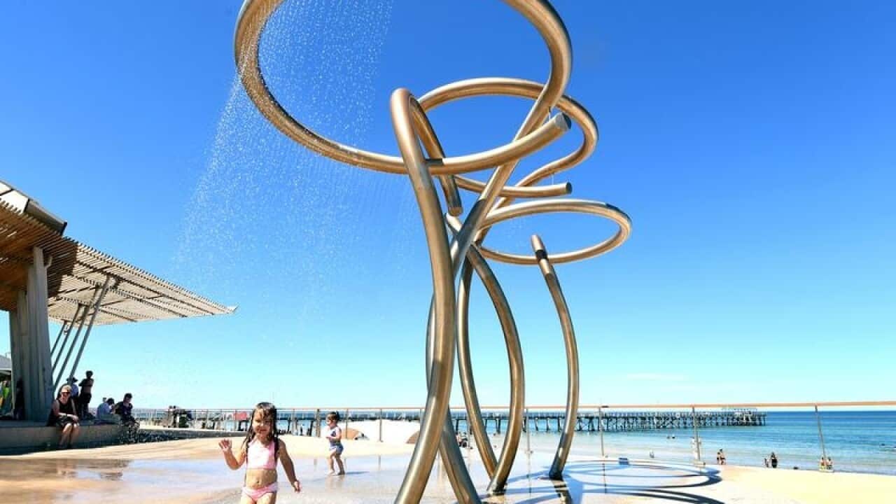 Kids play under a water feature in Adelaide.