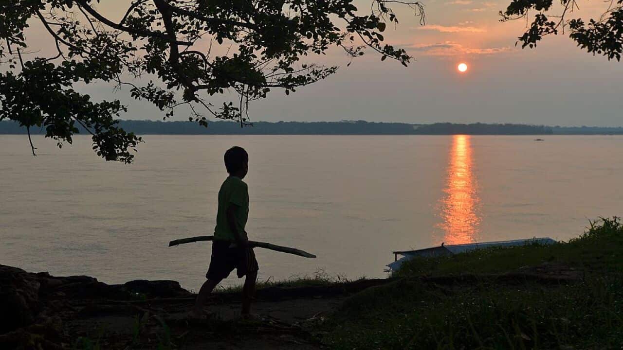 A Indigenous boy walks on the banks of the Amazon river.