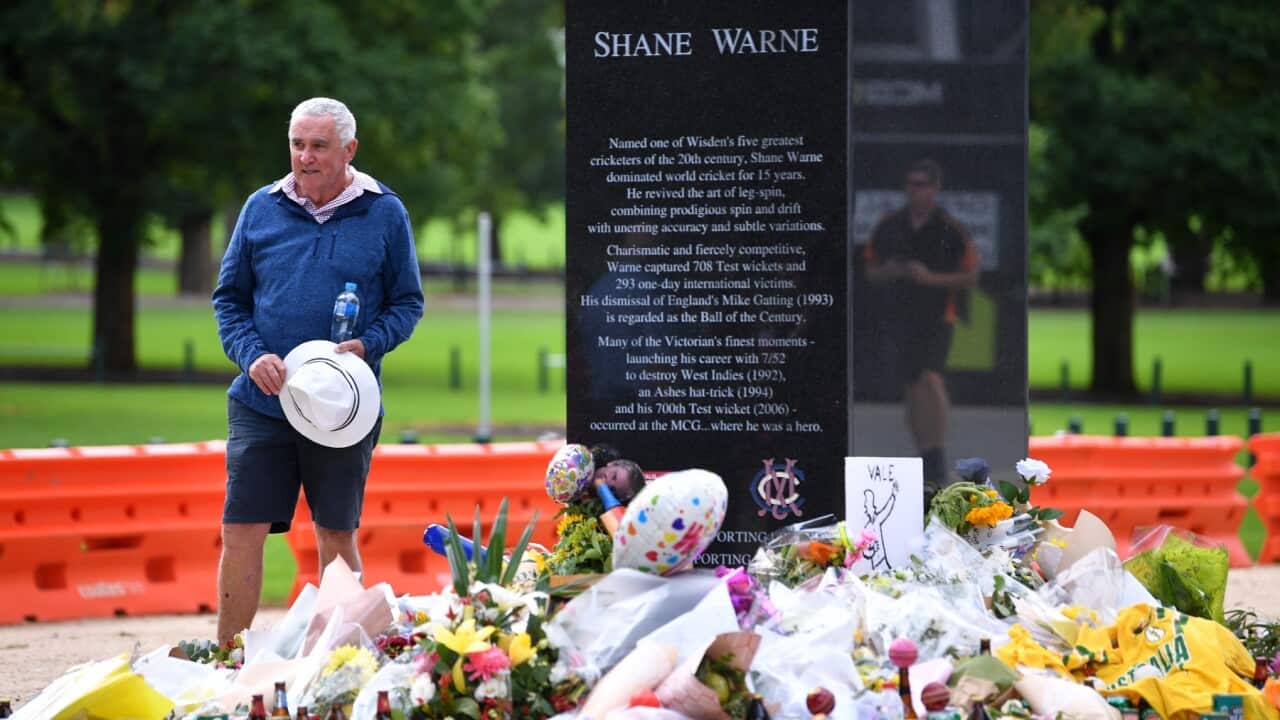 A person observes tributes to Australian cricketer Shane Warne at his statue outside the MCG in Melbourne