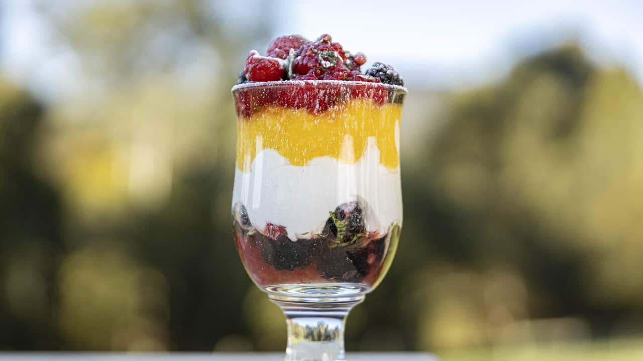 A big, tall glass holds a four-layer dessert.