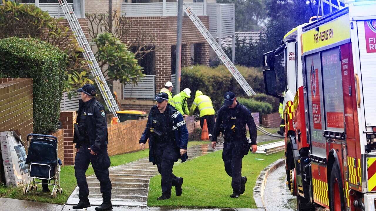 People in uniforms at a scene of a partial building collapse following an explosion.