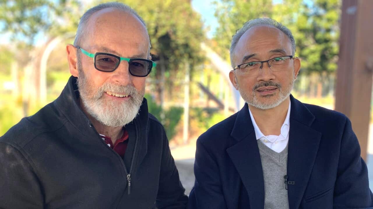 Two men in their 60s sitting on a park bench.