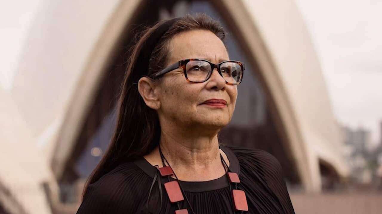 A woman posing for a photo outside the Sydney Opera House.
