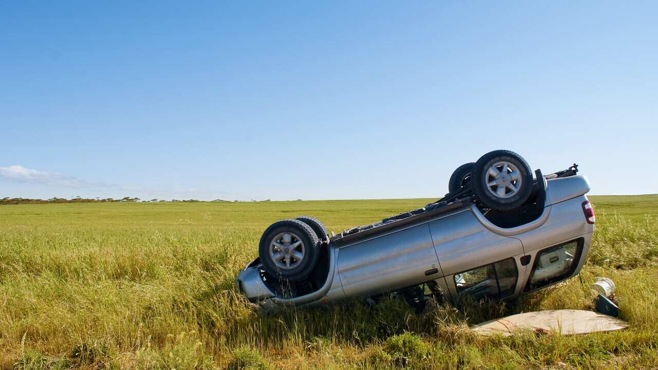 Car crashed on country road with field and sky