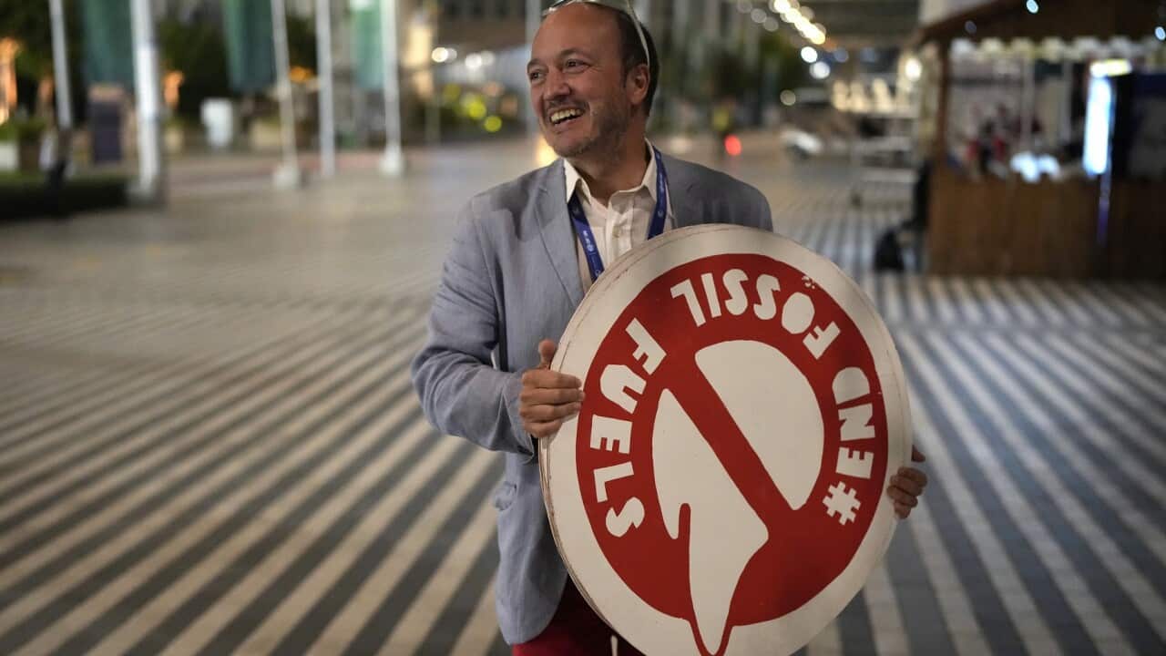 A man holds a sign that reads end fossil fuels at the COP28 (AAP)