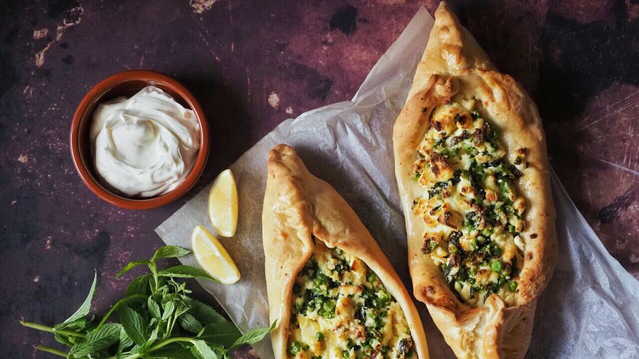 Pea, mint, and haloumi pide, served with wedges of lemon, yoghurt and fresh mint