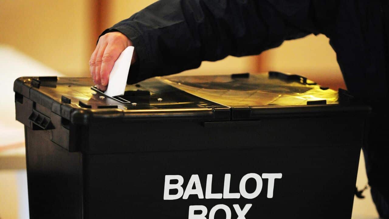 A voter placing a ballot paper in the ballot box.