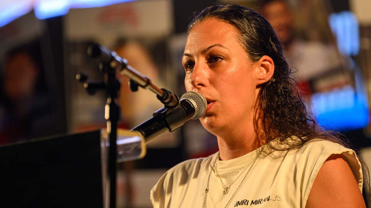 A woman in a white t-shirt speaking into a microphone