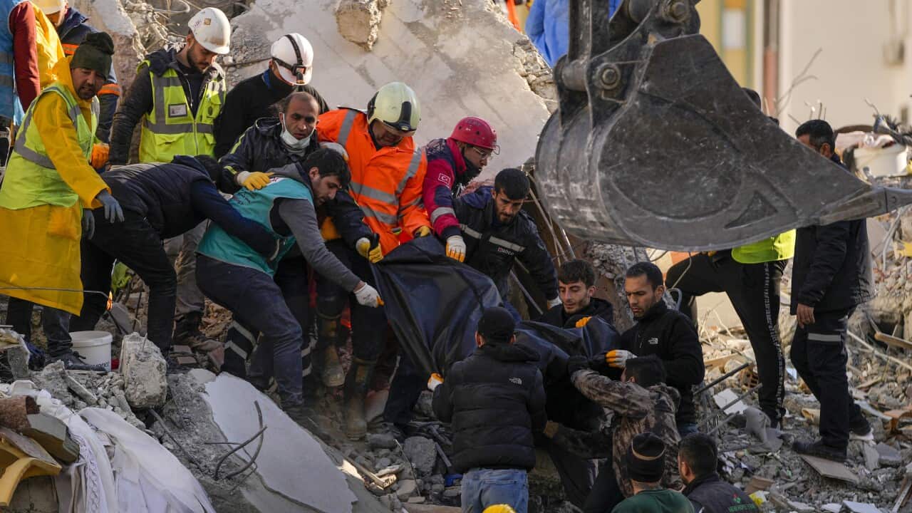 Rescue workers carry a body bag over rubble