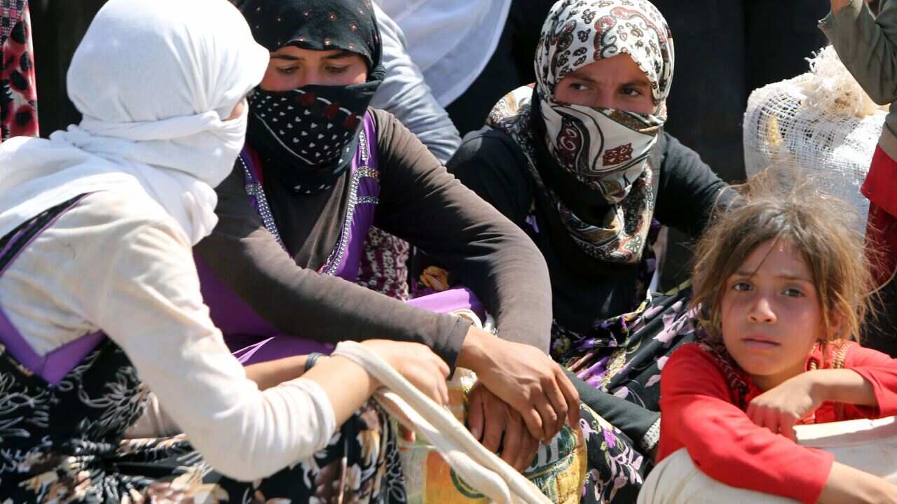 Displaced Iraqi Yazidi women gather sitting at the Bajid Kandala camp near the Tigris River, in Kurdistan's western Dohuk province. (AAP)