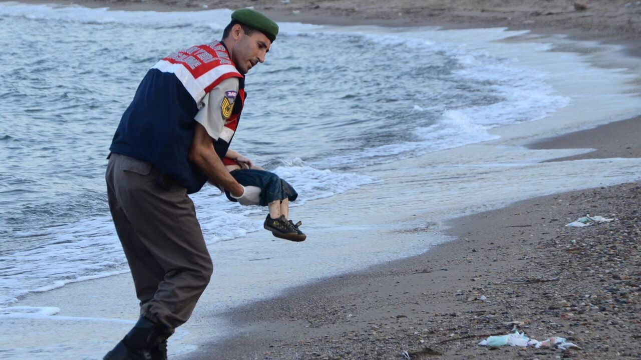 A Turkish police officer carries Alan Kurdi's body