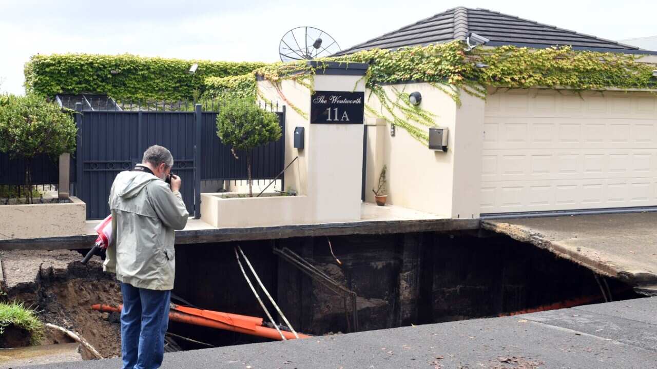 A man takes a photograph of a sinkhole which opened up in the suburb of Point Piper in Sydney on Wednesday, Feb. 8, 2017.
