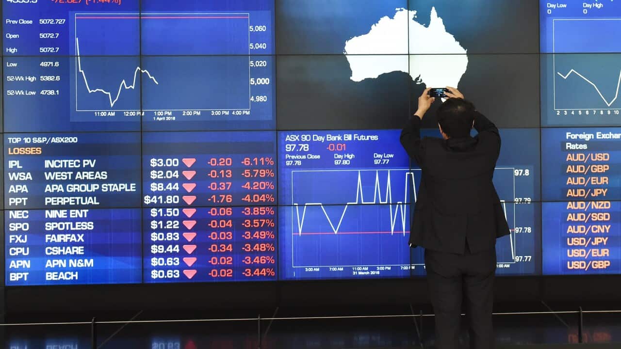 A tourist takes photos of the Australian Stock Exchange indicator board in Sydney (AAP)