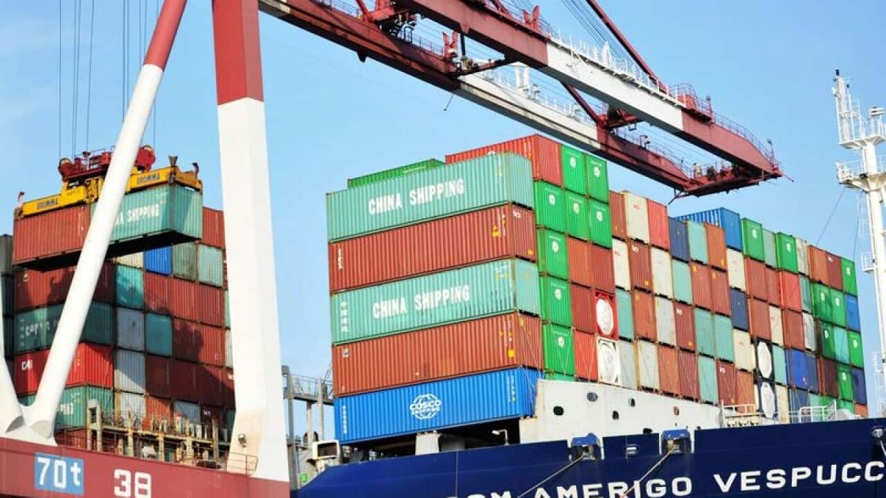 A crane loads a container onto a cargo ship in a Chinese port
