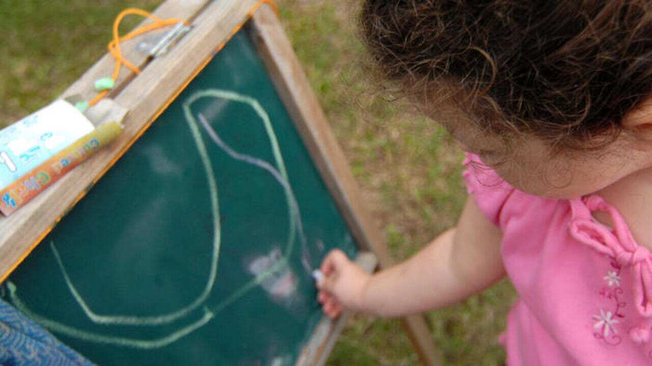 A stock image of a young girl drawing on a chalkboard in a child care centre in Brisbane, June 4, 2007. (AAP Image/Maria Zsoldos) NO ARCHIVING