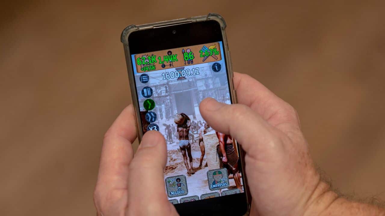 A person holding a mobile phone with a game on the screen.