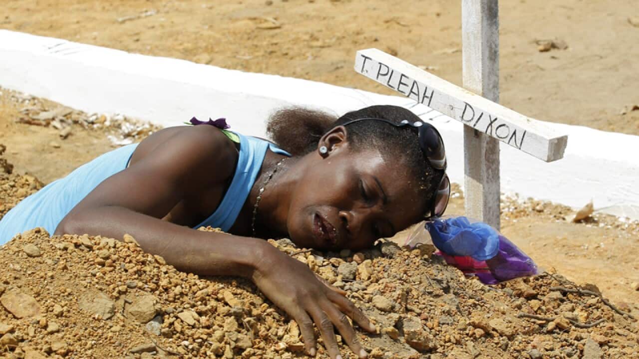 A Liberian woman mourns at the grave of her late brother
